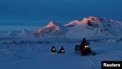 FILE: NPI (Norwegian Polar Institute) scientists ride their snowmobiles as the sun sets at the banks of Kongsfjord and the Kronebreen glacier near Ny-Aalesund, Svalbard, Norway, on April 10, 2023.