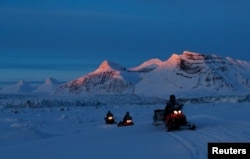 NPI (Norwegian Polar Institute) scientists ride their snowmobiles as the sun sets at the banks of Kongsfjord and the Kronebreen glacier near Ny-Aalesund, Svalbard, Norway, April 10, 2023.