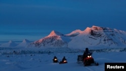 Ученые Норвежского полярного института (NPI) едут на снегоходах на берегу Конгсфьорда, недалеко от Ню-Алесунда, Шпицберген, Норвегия, 10 апреля 2023 г.