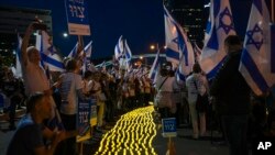 Israelis light candles as they protest plans by Prime Minister Benjamin Netanyahu's government to overhaul the judicial system, in Tel Aviv, Israel, April 22, 2023. (AP Photo/Tsafrir Abayov)