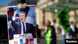 FILE: A placard with a portrait of French President Emmanuel Macron and the slogan "49.3, because it's my project" is seen as French workers gather on the eve of the ninth day of national pension reform strikes and protests, in Nice, France, March 22, 2023.
