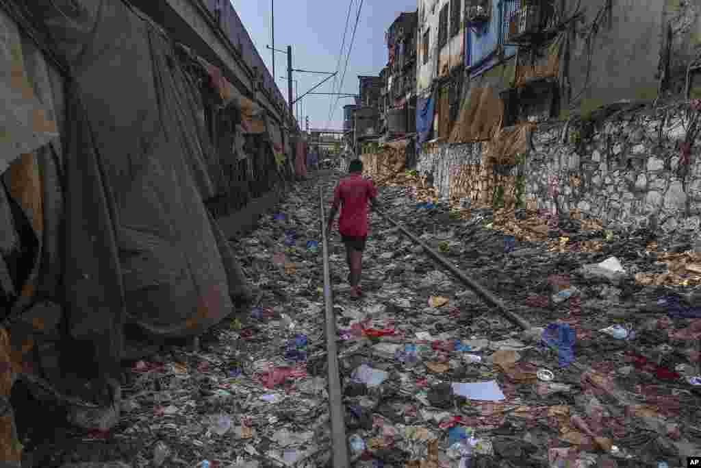 A man walks on a railway track littered with plastic and other waste materials on Earth Day in Mumbai, India.