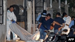 Forensic personnel remove the body of one of the eleven people killed in a pool hall in Choloma, about 180 km north of Tegucigalpa, early on June 25, 2023. 