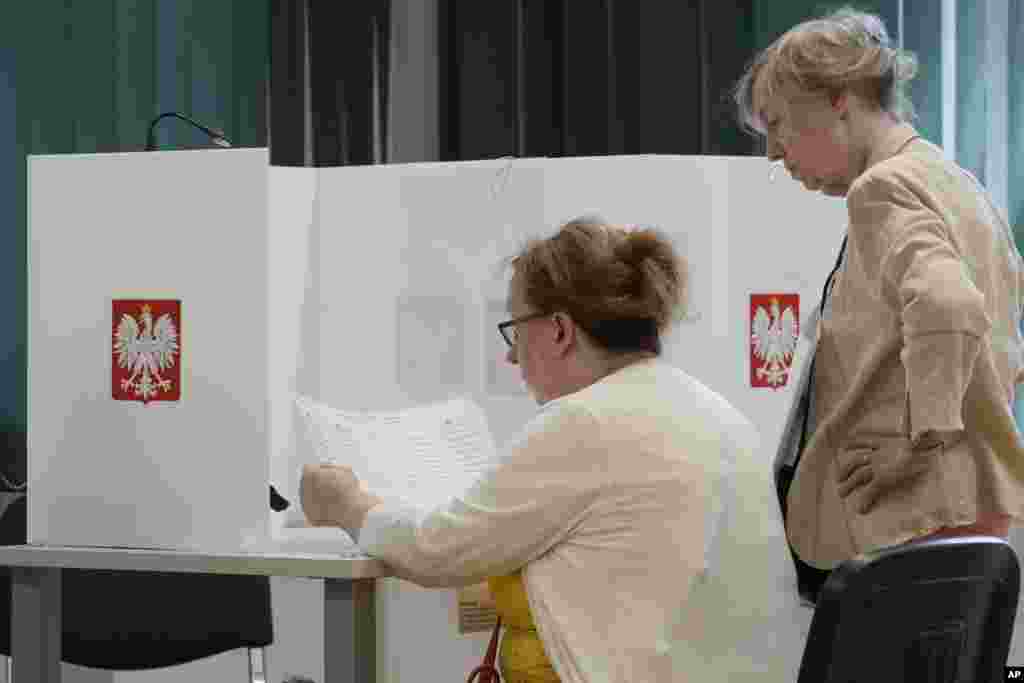 Voters check a ballot at a polling station during the European Elections during the European Parliament election in Warsaw, Poland, June 9, 2024.