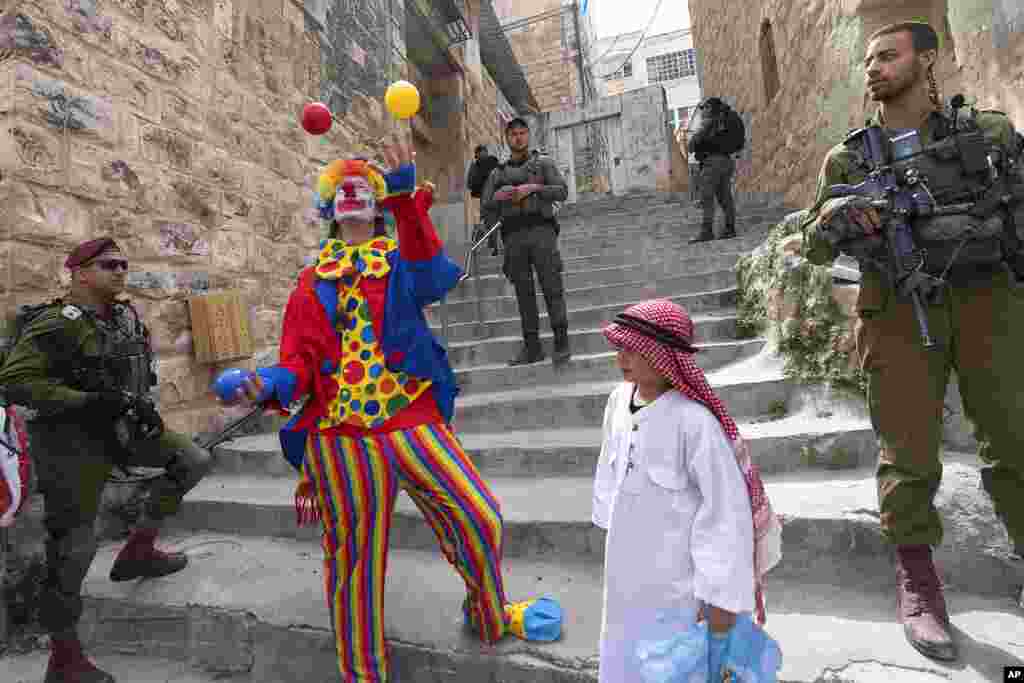 Jewish settlers dressed in costumes celebrate the Jewish holiday of Purim as soldiers secure the march in the West Bank city of Hebron.