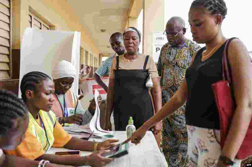 A voter looks on as another gets her information checked in the Bimodal Voter Accreditation System (BVAS) by an Independent National Electoral Commission (INEC) official at a polling station in Agege, Lagos, on February 25, 2023,&nbsp;