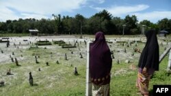 FILE - Widow Sitirokayah Salaeh (R) visits the cemetery in Tak Bai where her late husband Mahamad Lohbako is buried together with other anti-government demonstrators who died during the 2004 Tak Bai incident, in Narathiwat Province, Oct. 24, 2019. 