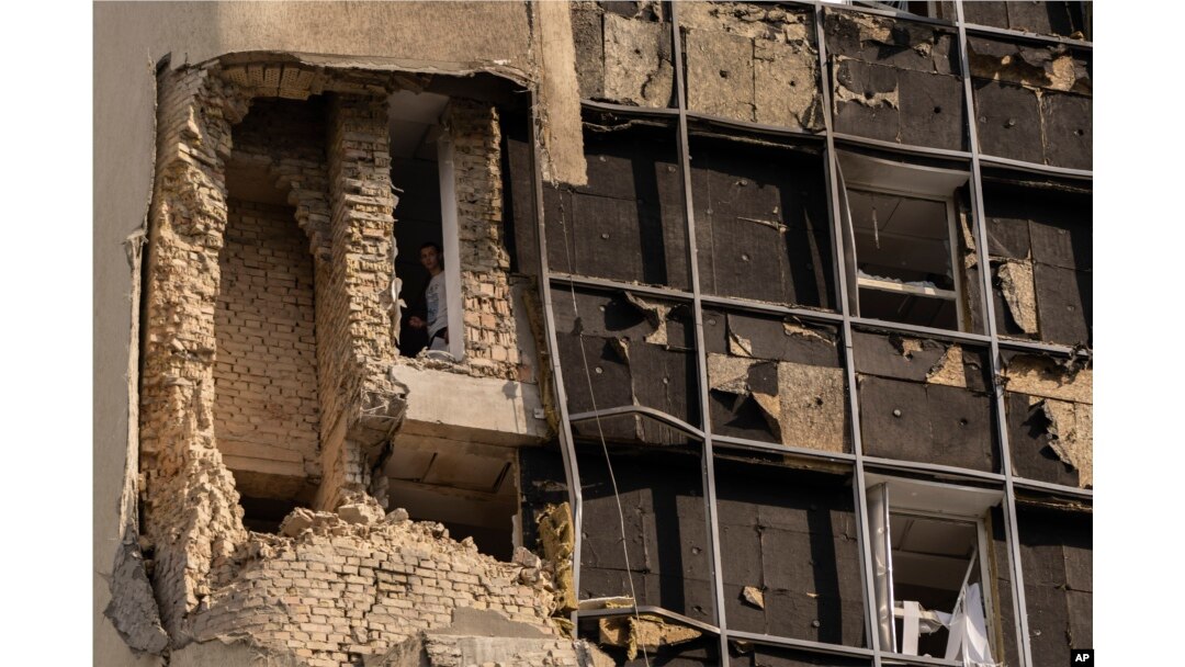 Seseorang melihat ke luar jendela gedung pemerintah yang rusak di Kyiv, Ukraina, pada 2 Agustus 2023, menyusul serangan pesawat tak berawak Rusia. (Foto: AP)