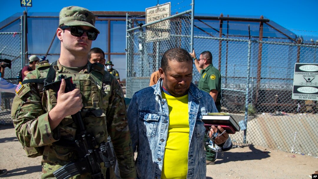 Tentara Amerika Serikat mengawal para migran untuk diproses oleh pihak imigrasi setelah memasuki wilayah El Paso, Texas dari Ciudad Juarez, Meksiko, 10 Mei 2023. (Foto: Andres Leighton/AP Photo, File)