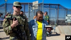 FILE - Migrants are escorted by a U.S. Army soldier after entering into El Paso, Texas from Ciudad Juarez, Mexico, to be processed by immigration authorities, May 10, 2023. 