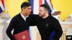 Perdana Menteri Inggris Rishi Sunak, kiri, memeluk Presiden Ukraina Volodymyr Zelenskyy setelah menandatangani dokumen di Kyiv, Ukraina, 12 Januari 2024. (Foto: AP)