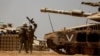 Israeli soldiers walk near a tank and ammunition piles near the Israel-Gaza Border, in southern Israel, May 9, 2024.