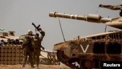 以色列士兵在以色列-加沙边境附近的坦克和弹药堆附近。(2024年5月9日)