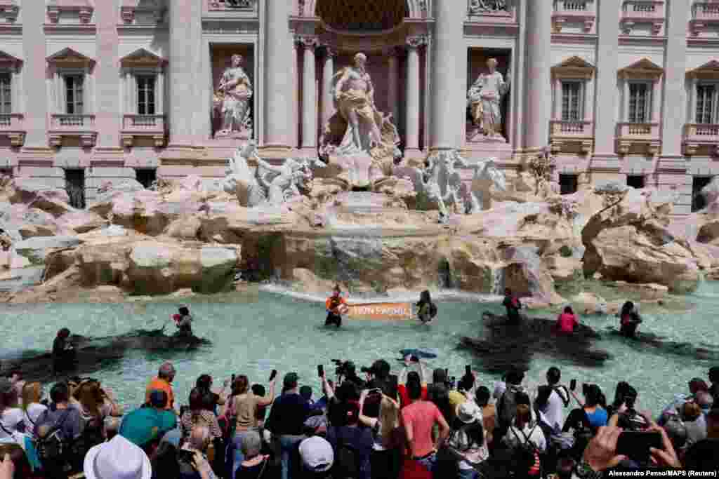 Climate activists pour vegetable charcoal in the Trevi Fountain water, during a demonstration against fossil fuels, in Rome, Italy, in this image obtained from social media.