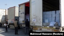 (FILE) Men inspect trucks carrying aid from UN World Food Programme following a deadly earthquake in Syria