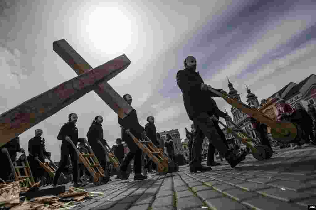 People wearing white masks push carts as they take part in the Czech Easter rattling traditional ritual to mark Good Friday, which recalls for Christians the crucifixion of Jesus Christ ahead of Easter Sunday, in Ceske Budejovice.