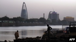 FILE — Sudanese men stand opposite the Greater Nile Petroleum Operating Company building overlooking the Nile in Khartoum, April 18, 2010.