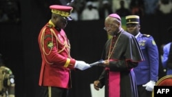 Archbishop of Libreville Jean-Patrick Iba-Ba, right, receives the report from Transitional President General Brice Oligui Nguema at the opening of the National Dialogue in Gabon at the Libreville Gymnasium, April 2, 2024.