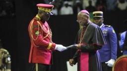 Archbishop of Libreville Jean-Patrick Iba-Ba, right, receives the report from Transitional President General Brice Oligui Nguema at the opening of the National Dialogue in Gabon at the Libreville Gymnasium, April 2, 2024.