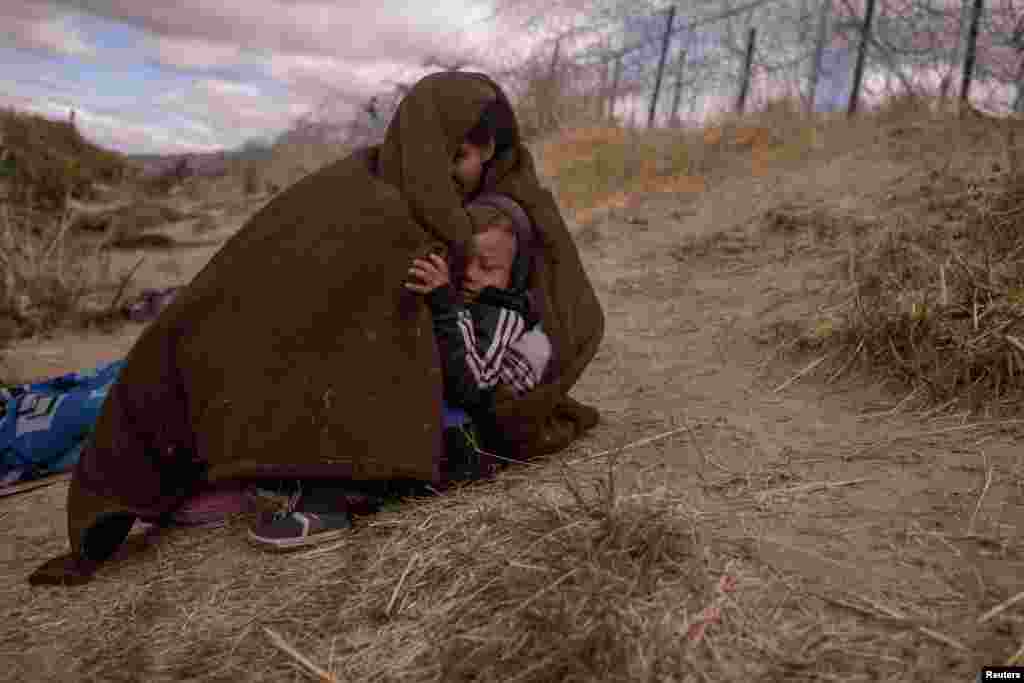 Jolimar, an 18-year-old migrant from Venezuela, shelters her two-year-old son Gail from the cold and blustery weather&nbsp;as they search for an entry point into the U.S.&nbsp;along the bank of the Rio Grande river in El Paso, Texas, March 25, 2024.