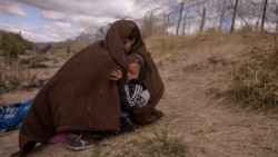 Jolimar, an 18-year-old migrant from Venezuela, shelters her two-year-old son Gail from the cold and blustery weather along the bank of the Rio Grande river in El Paso, Texas, March 25, 2024. 