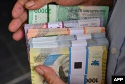 Seorang pria memegang uang kertas rupiah baru yang akan diberikan kepada anggota keluarganya selama perayaan Idulfitri pada 28 Maret 2024. (Foto: AFP)