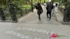 Sejumlah warga berjalan melewati grafiti yang dibuat untuk menarik perhatian terkait kasus kematian Jordan Neely di Washington Square Park, pada 5 Mei 2023. (Foto: AP/Brooke Lansdale)