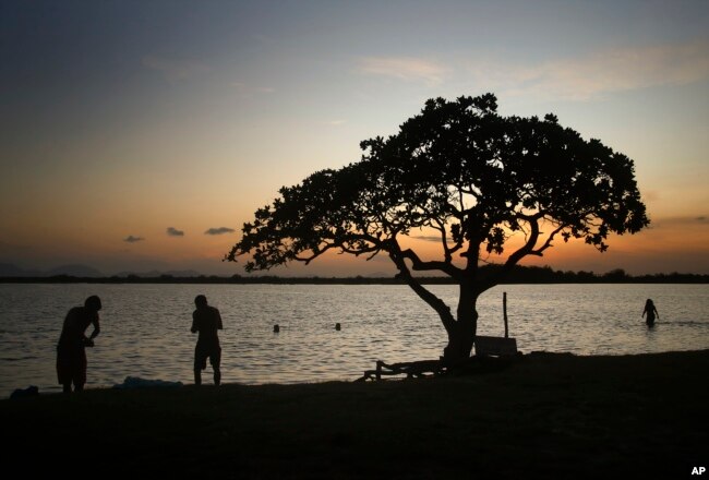 Indigenous people bathe in Caracarana lake at sunset, in Normandia, on the Raposa Serra do Sol Indigenous reserve in Roraima state, Brazil, Monday, March 13, 2023. (AP Photo/Edmar Barros)