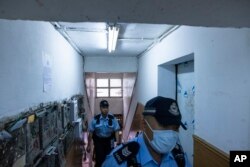 Polisi berjalan di sebuah apartemen di mana tiga anak dibunuh di Sham Shui Po, Hong Kong, Senin, 5 Juni 2023. (AP/Louise Delmotte)