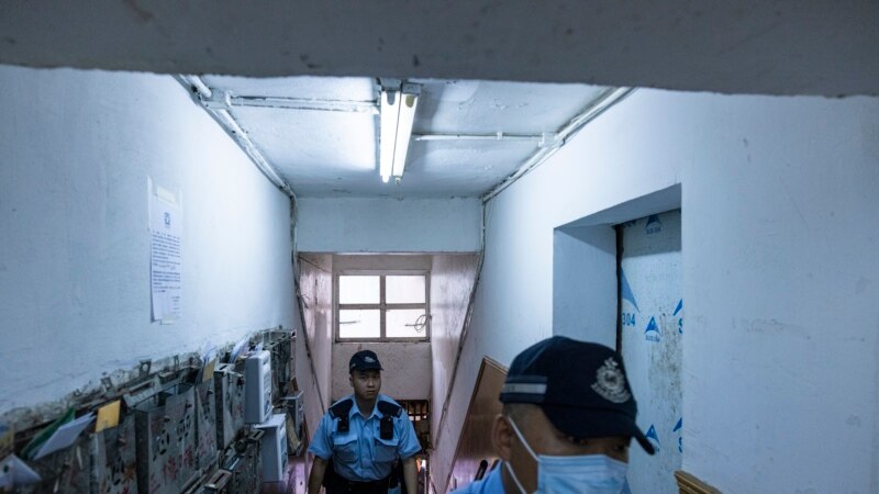 Polisi berjalan di sebuah apartemen di mana tiga anak dibunuh di Sham Shui Po, Hong Kong, Senin, 5 Juni 2023. (AP/Louise Delmotte)