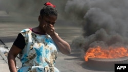 A woman walks past burning tires during a demonstration following the resignation of Haiti's Prime Minister Ariel Henry, in Port-au-Prince, Haiti, on March 12, 2024.