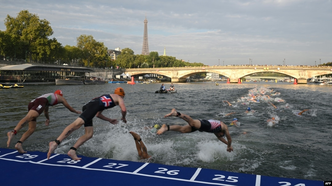 Sejumlah atlet triathlon terjun ke Sungai Seine dengan Menara Eiffel sebagai latar belakang dalam acara Tes Olimpiade Triathlon Dunia 2023 putra di Paris, 18 Agustus 2023. (Foto: AFP)