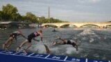 FILE - Triathletes dive into The Seine river with the Eiffel Tower in the background during the men's 2023 World Triathlon Olympic Games Test Event in Paris. (Photo by Bertrand GUAY / AFP)