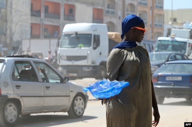 FILE - A vendor sells plastic sachets filled with drinkable water in Dakar, on Aug. 23, 2023.