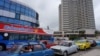 Un autobús turístico pasa junto a los automóviles que hacen fila para llenar sus tanques de gasolina en La Habana, Cuba, el 11 de diciembre de 2023.