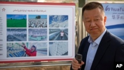 中國政府組織外國記者參觀新疆維吾爾自治區阿克蘇期間，新疆華孚色紡集團有限公司總經理李強在其公司宣傳板前講話。 （2021年4月20日）