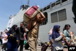 Penumpang turun dari kapal perang TNI Angkatan Laut Banda Aceh di pelabuhan Tanjung Emas di Semarang, yang membawa mereka mudik saat gratis dari Jakarta menjelang Idulfitri, 6 April 2024. (DEVI RAHMAN/AFP)
