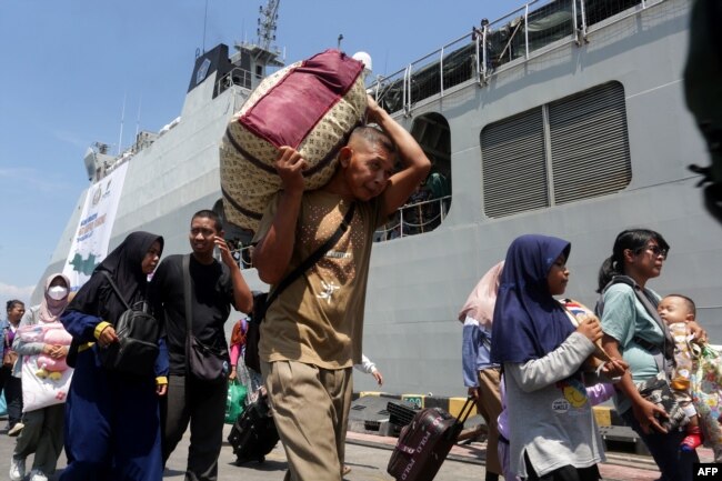 Penumpang turun dari kapal perang TNI Angkatan Laut Banda Aceh di pelabuhan Tanjung Emas di Semarang, yang membawa mereka mudik saat gratis dari Jakarta menjelang Idulfitri, 6 April 2024. (DEVI RAHMAN/AFP)