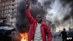 FILE: in an earlier clash this week, an opposition supporter holds a stone during clashes with Kenya Police Officers at the informal settlement of Mathare in Nairobi, Kenya. Taken March 27, 2023. 