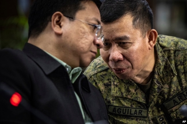 FILE - Col. Medel Aguilar, right, spokesperson for the Armed Forces of the Philippines, whispers to Jonathan Malaya, spokesperson for the National Security Council, as they take part in a press conference on the recent actions by the Chinese coast guard against Philippine vessels in the South China Sea, at the Philippine Department of Foreign Affairs in Manila on Aug. 7, 2023.