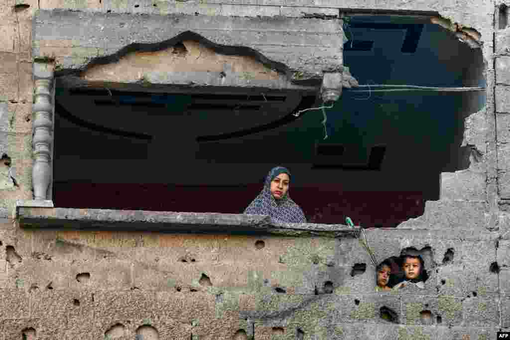 A Palestinian woman and children look on following Israeli bombardment on Rafah, in the southern Gaza Strip, amid continuing battles between Israel and the Palestinian militant group Hamas. (Photo by Mohammed Abed / AFP)