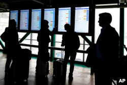 para penumpang memeriksa layar informasi penerbangan American Airlines untuk mengetahui status penerbangan mereka di Bandara Internasional O'Hare di Chicago, Rabu, 22 Februari 2023. Lebih dari 100 penerbangan dibatalkan karena sebagian wilayah Chicago mengalami hujan dan es yang membekukan, sementara yang lain melihat hujan lebat. (AP/Nam Y.Huh)