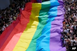 FILE - Peserta mengibarkan bendera pelangi saat Parade "Pride" di Bangkok, Thailand, 4 Juni 2023. Anggota parlemen di majelis rendah Parlemen Thailand dengan suara bulat menyetujui RUU Kesetaraan Pernikahan, Rabu, 27 Maret 2024. (AP/Sakchai Lalit, File)