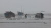 Dua pria berjalan di sepanjang peternakan udang dan kepiting yang terendam banjir akibat hujan lebat saat Topan Remal melewati daerah Shyamnagar di Satkhira, Bangladesh. (Reuters)&nbsp;