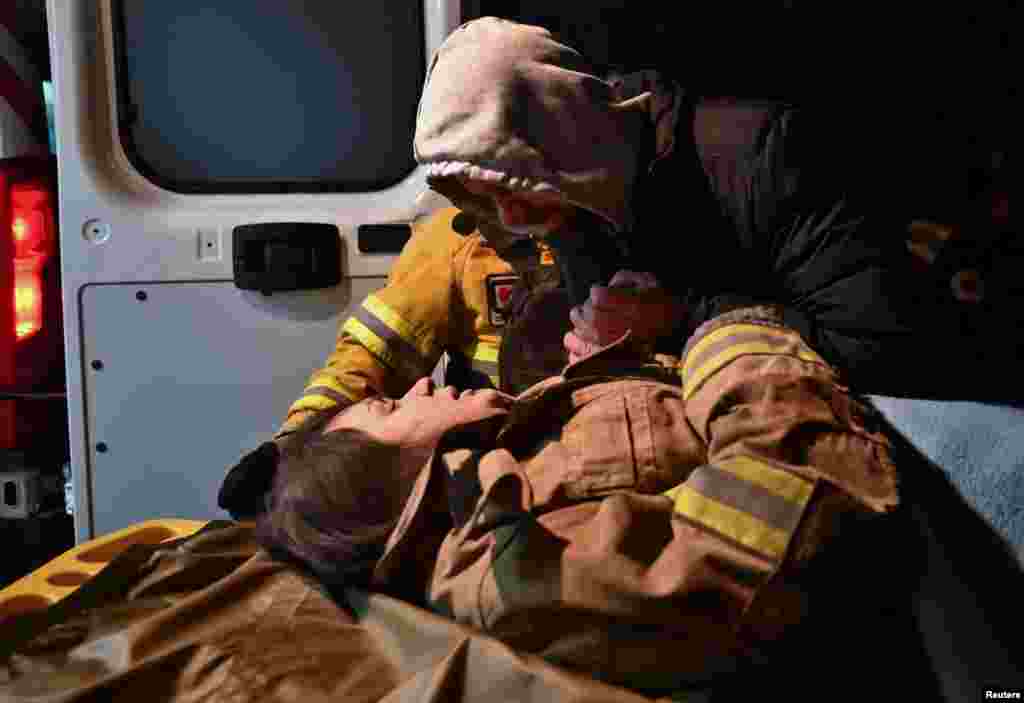 Јуриј ја држи за рака својата бремена роднина Ана (27), откако таа беше спасена од станбена зграда која беше тешко оштетена од руски ракетен напад во Запорожје, Украина.