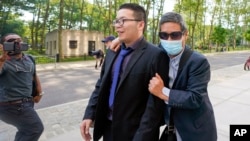 FILE - Zhu Yong, right, tries to shield himself from photographers as he leaves federal court, May 31, 2023, in Brooklyn, N.Y. Zhu was one of three men convicted in an escalating series of scare tactics aimed at repatriating a former Chinese official living in New Jersey. 