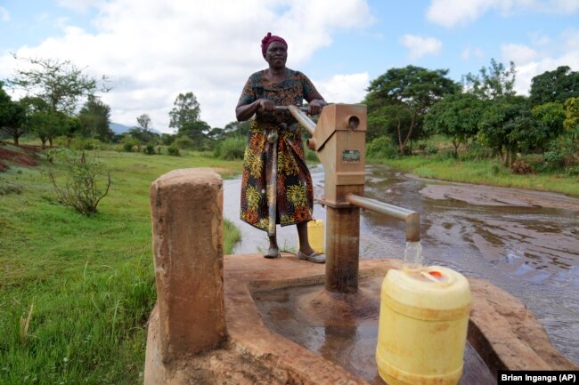 Rhoda Peter fills containers with water from a sand dam in Makueni County, Kenya on Friday, March 1, 2024. She was fetching water to clean utensils and wash clothes. (AP Photo/Brian Inganga)