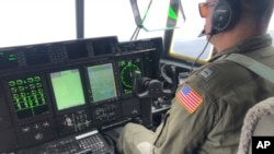 A crew member sits aboard a Coast Guard HC-130 Hercules airplane as it flies about 900 miles east of Cape Cod, Mass., during the search for the 21-foot submersible Titan, June 21, 2023. (U.S. Coast Guard via AP)