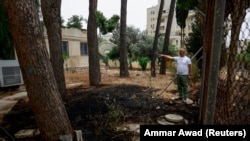 Seorang pria menunjukkan bekas kebakaran di markas UNRWA, di Yerusalem, 10 Mei 2024. (Foto: REUTERS/Ammar Awad)