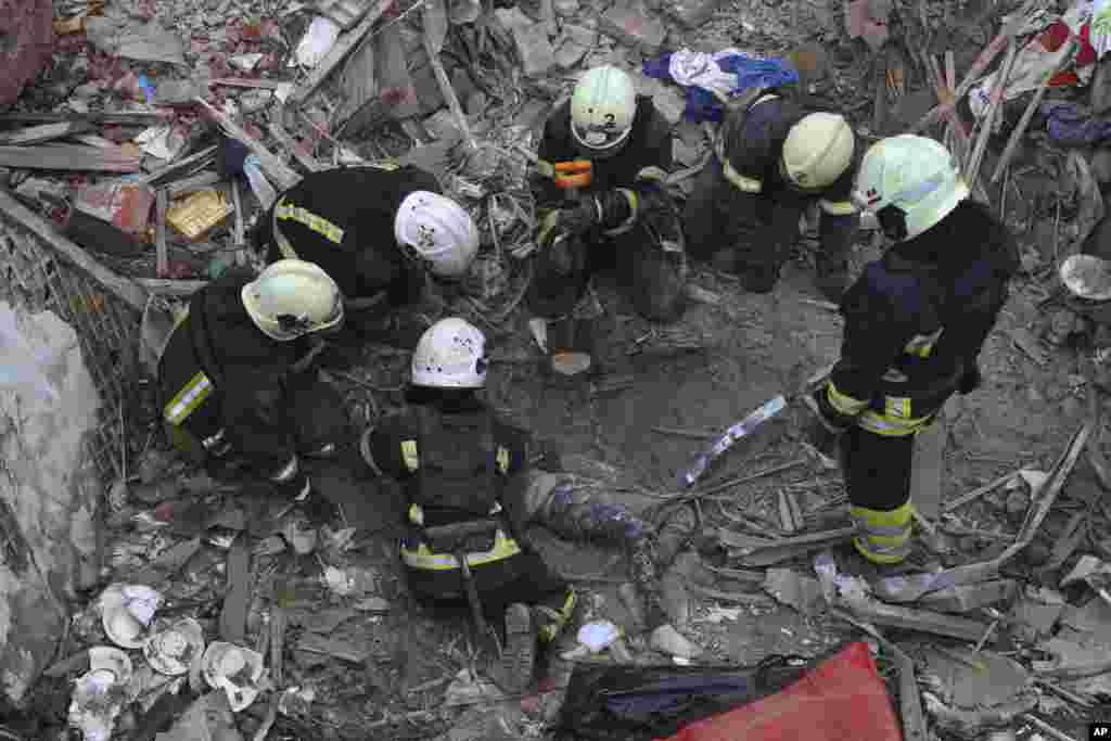 Emergency workers retrieve the body of a 10-year old boy who was killed in a Russian air attack that hit a multistory building in central Kharkiv, Ukraine.(AP Photo/Alex Babenko)